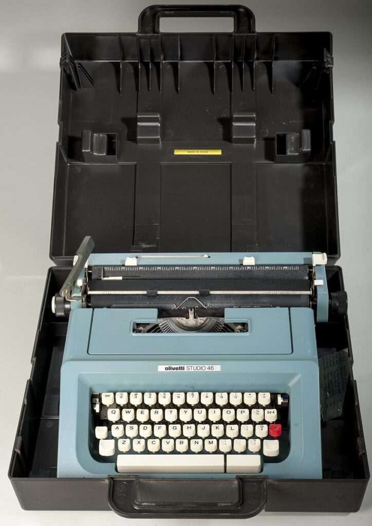 a blue typewriter sits in a black open case