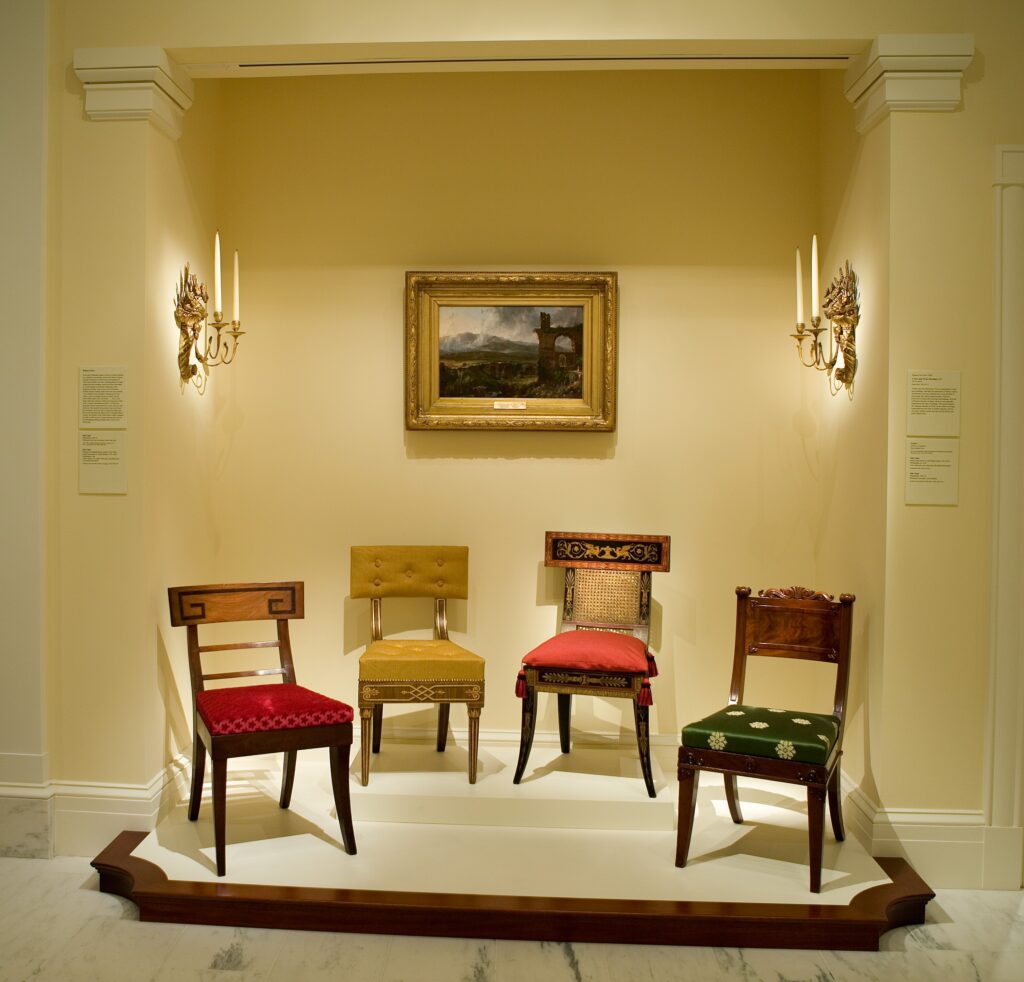 a group of four different armchairs sit on a raised dais